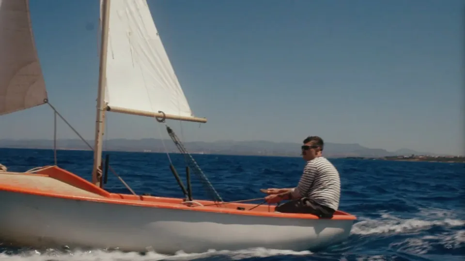 Matteo Leone su una piccola barca a vela bianca e arancione in mare aperto
